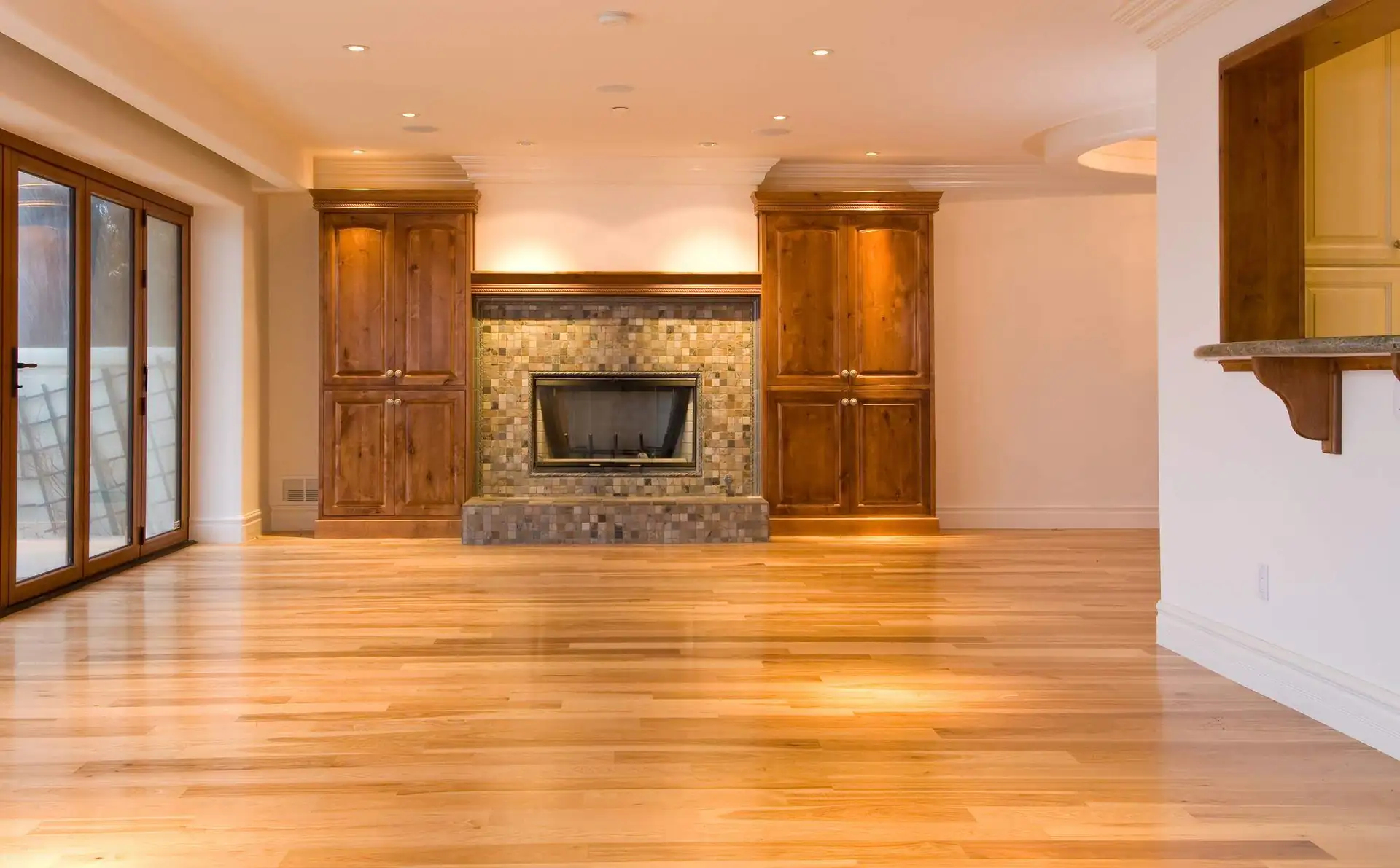 A natural oak floor glowing in front of a stone fireplace and built-ins, installed by Forever Flooring